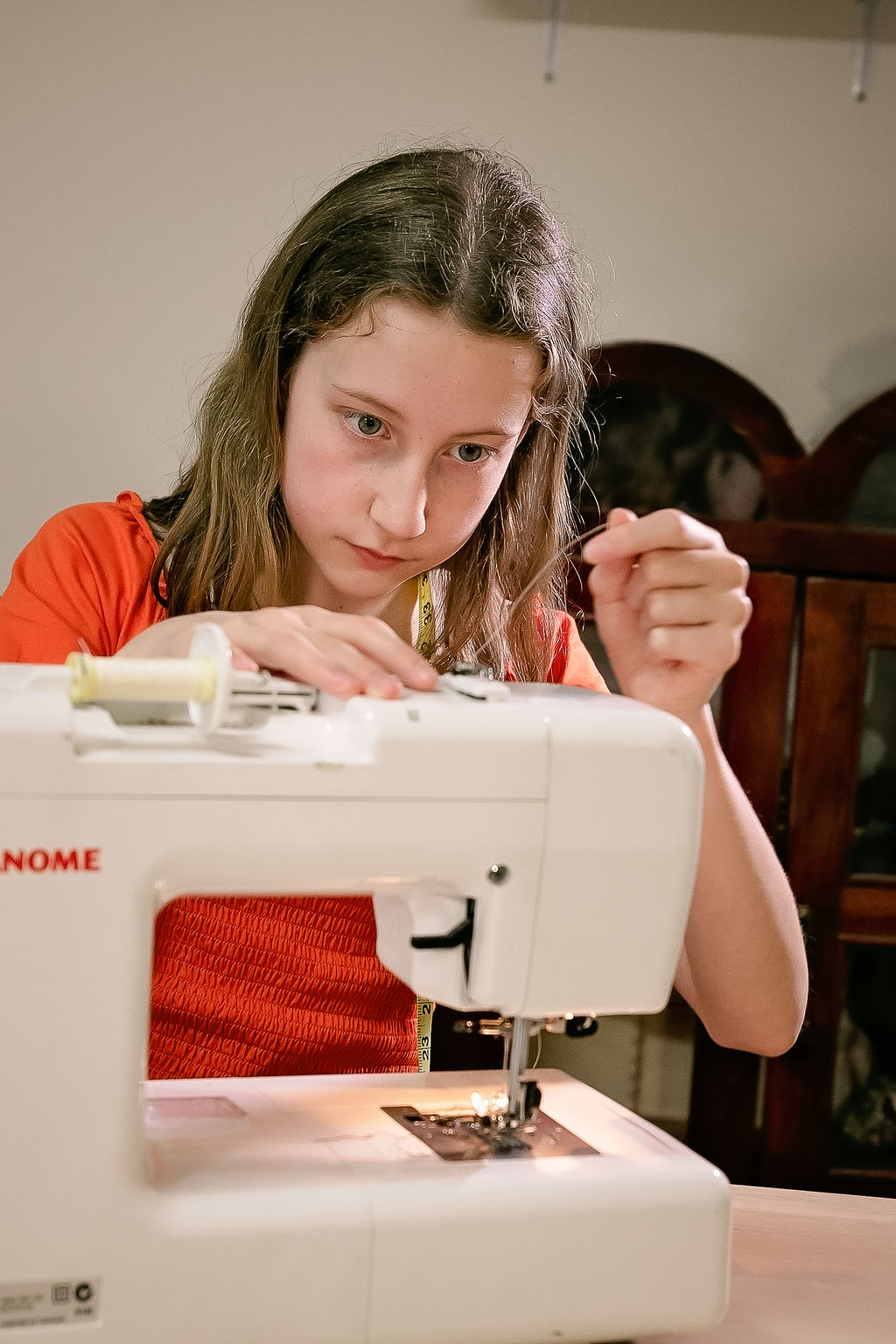 Girl learning to thread the sewing machine